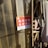 A red sign with white Chinese text is posted on a wall. The background consists of transparent plastic strips. To the side, there is a metal frame with a hanging fabric or garment.