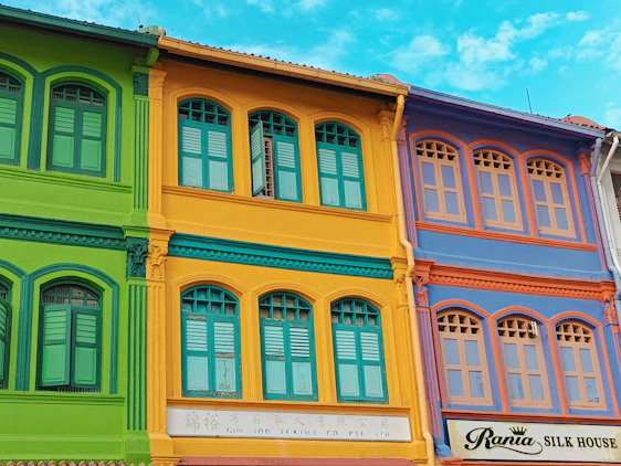 Before and after images of a freshly painted Alicante building facade showing vibrant crimson and forest green tones.