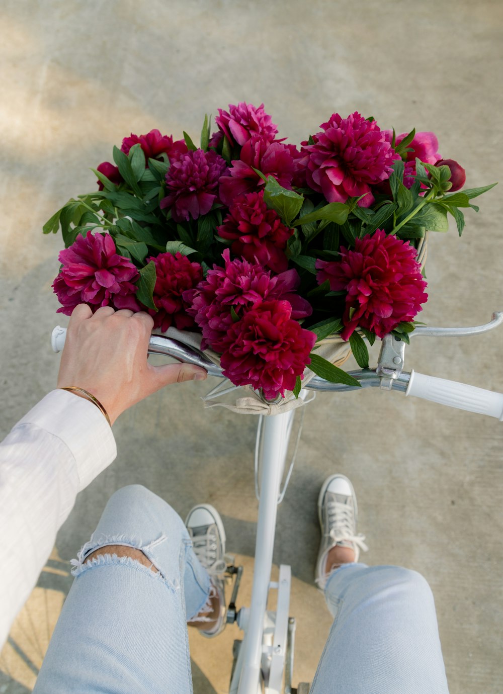 a person on a bicycle holding a bouquet of flowers