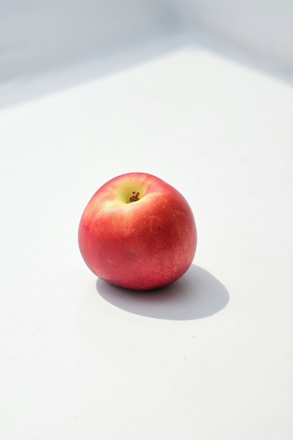 a red apple sitting on top of a white table