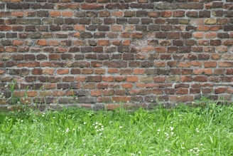 A retaining wall made from textured brickwork supporting a raised garden bed with colorful plants.