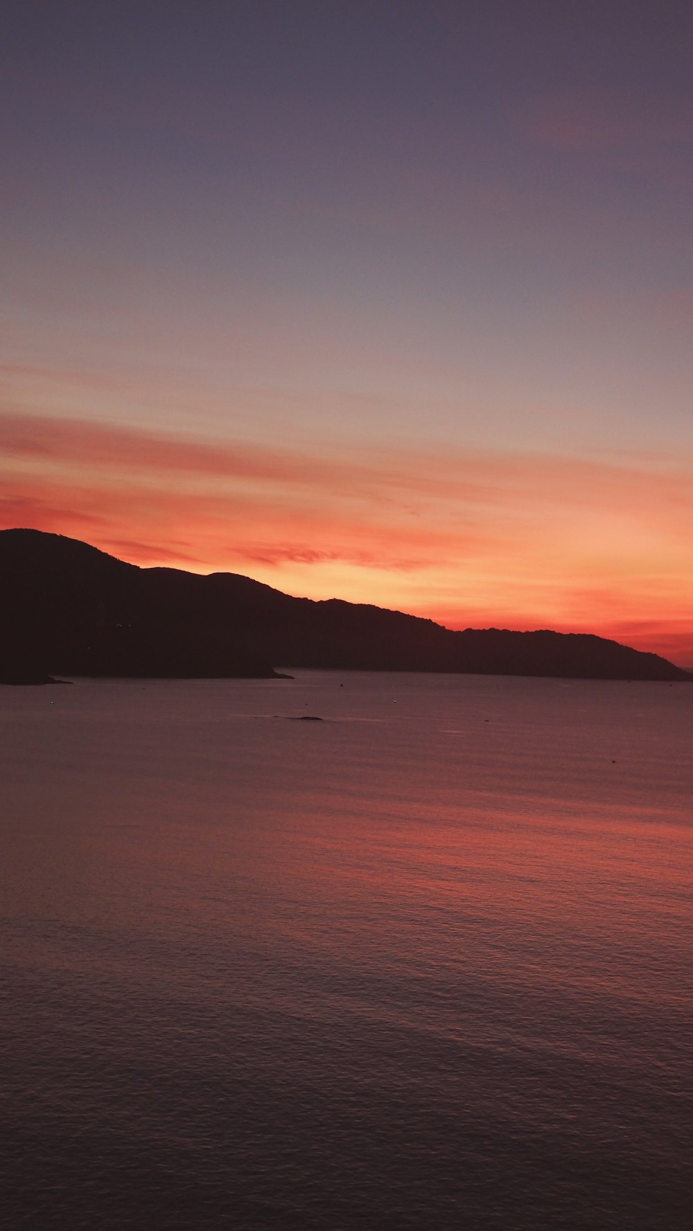 a sunset over a body of water with mountains in the background