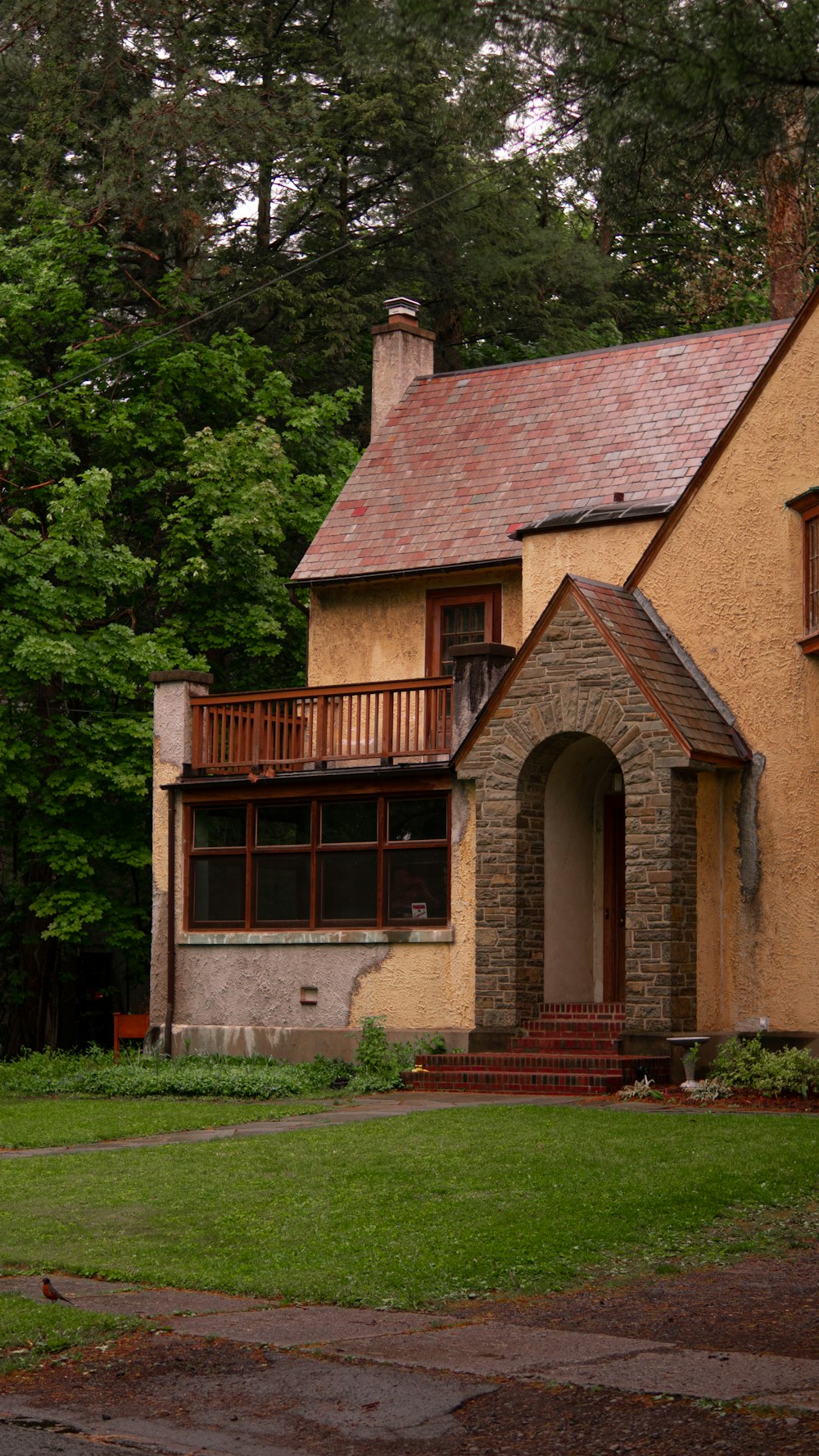 a yellow house with a red roof and a porch