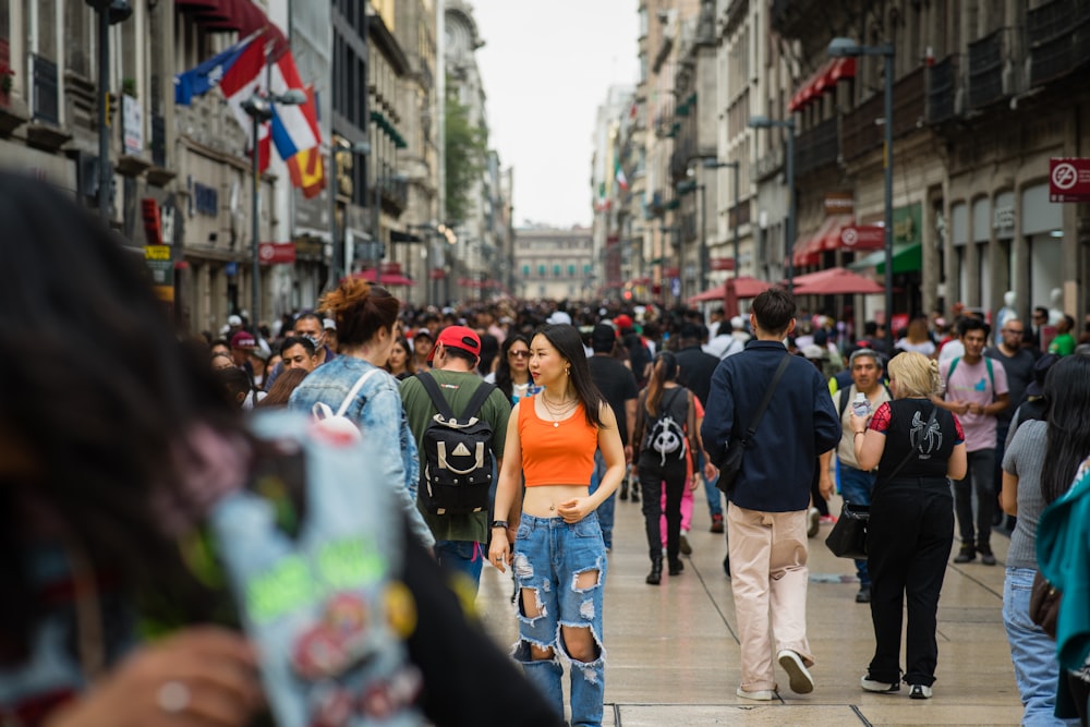 a crowd of people walking down a street next to tall buildings