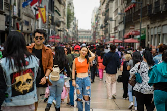 a group of people walking down a street next to tall buildings