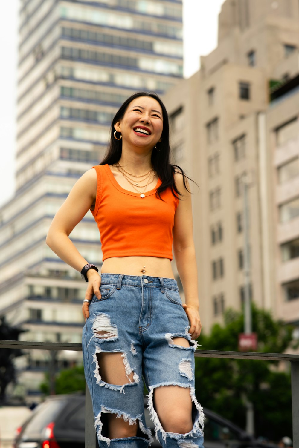 a woman in an orange top and ripped jeans