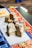 A close-up view of intricately carved wooden stamps with floral designs. These stamps are placed on a table covered with colorful fabric, displaying vibrant patterns such as floral and plaid prints.