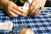 Close-up of hands folding a handwritten recipe card with rich, textured paper.