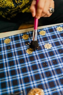 A close-up of a student delicately applying gold foil on a Tanjore painting canvas.