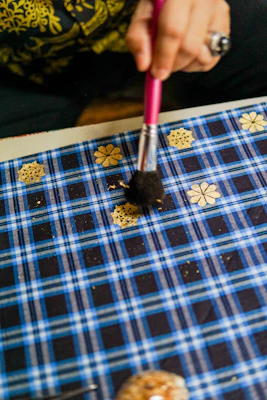 Manicurist carefully applying golden nail art details with a fine brush