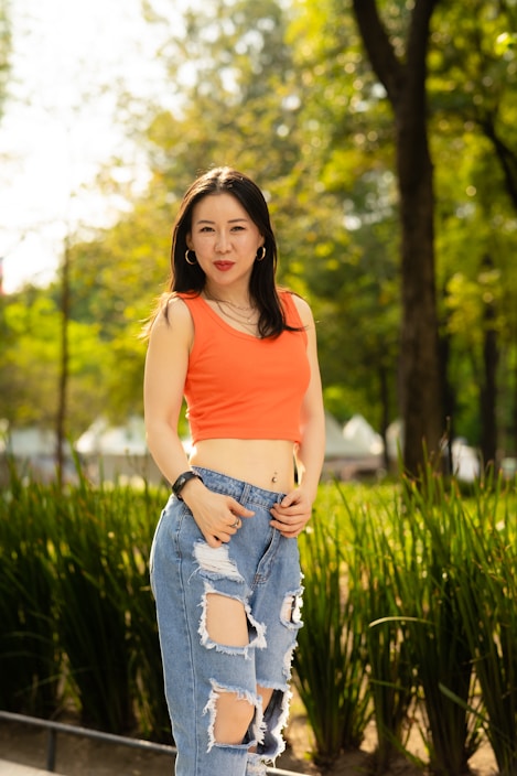 A model wearing a colorful t-shirt and jeans in a sunny park.