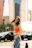 A dynamic outdoor shot of a female model in motion, wearing casual chic attire.