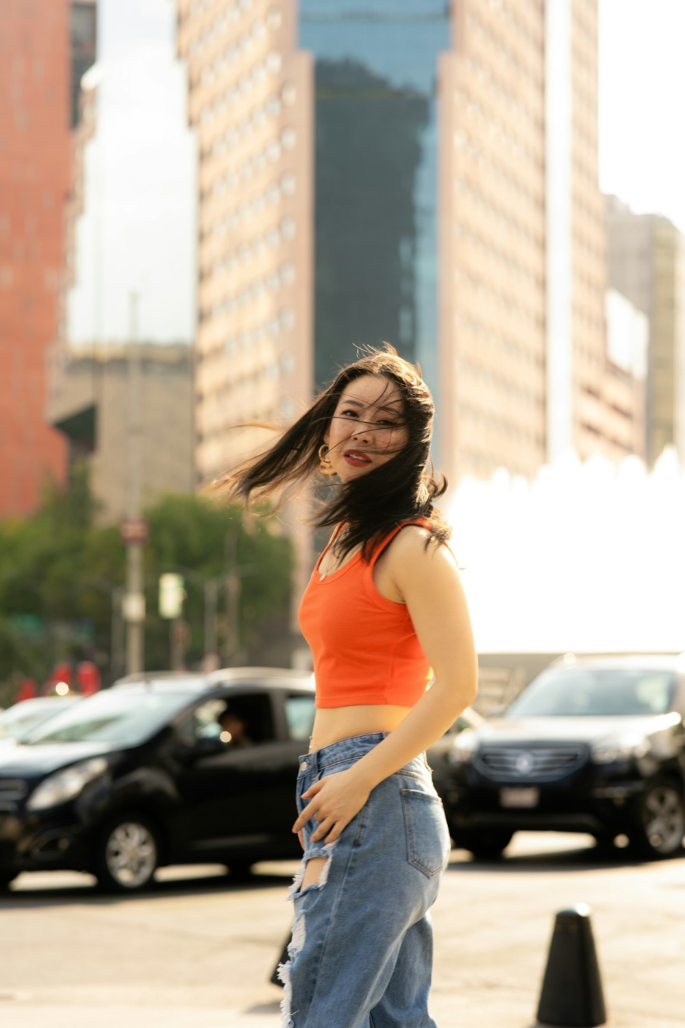 a woman in an orange top is standing on a sidewalk
