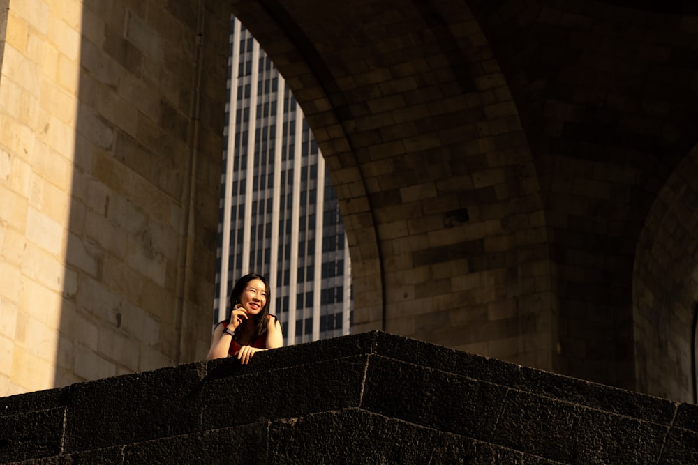 a woman talking on a cell phone while standing on a ledge