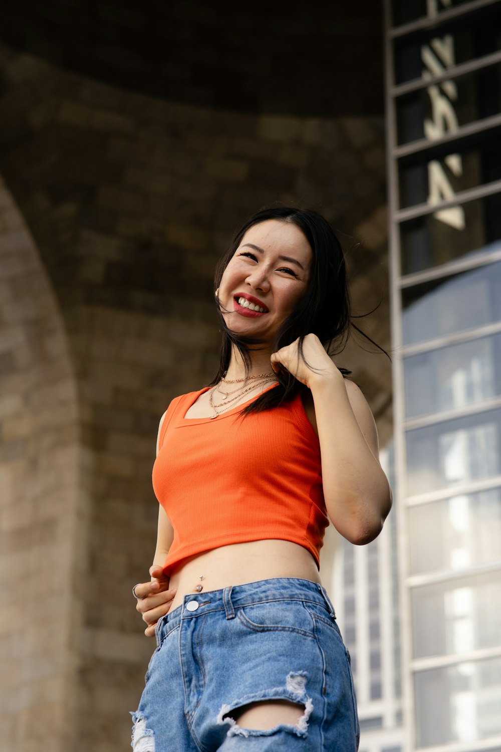 a woman in an orange shirt and ripped jeans