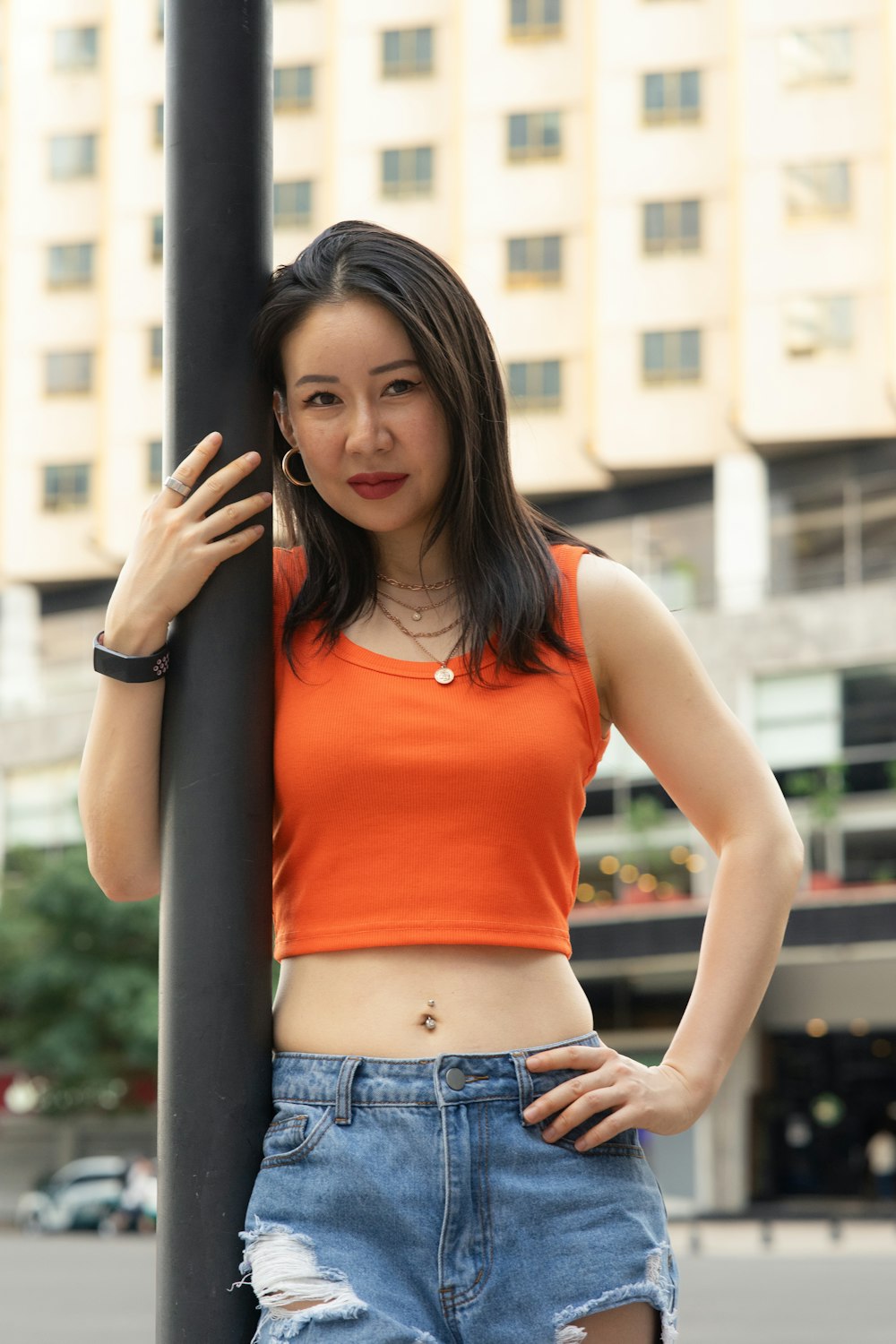 a woman leaning on a pole with her hands on her hips