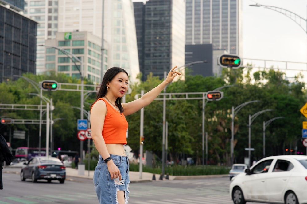 a woman standing on a street corner pointing at a traffic light