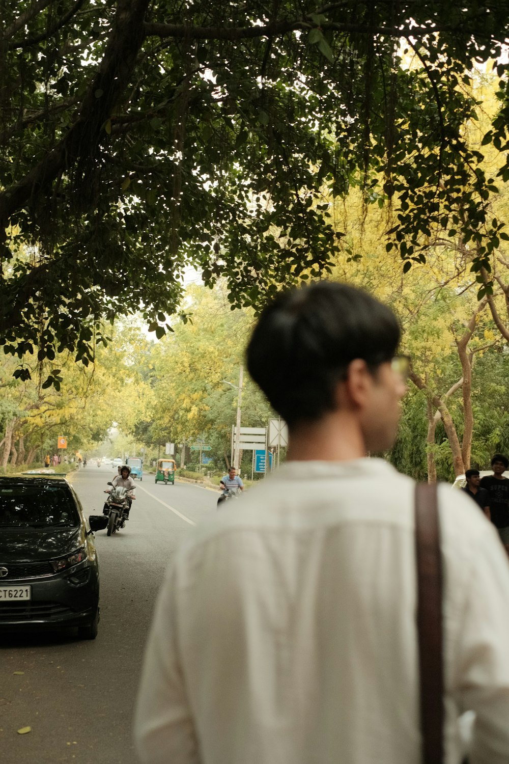 a man walking down a street next to a black car