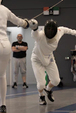 Focused adult fencer practicing precise moves during a competitive training session.