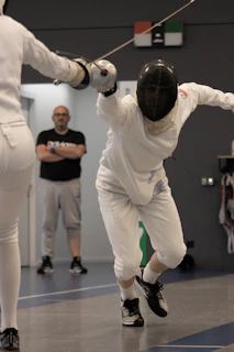 Close-up of a coach giving personalized tips to a teenage fencer during an intense training session