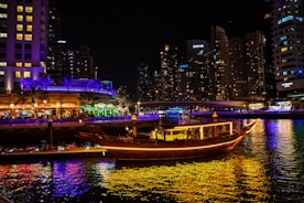Elegant dhow boat floating on calm waters lit by lanterns at night.