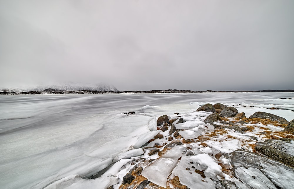 a large body of water surrounded by snow covered rocks
