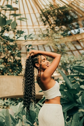 a woman with long hair standing in a greenhouse