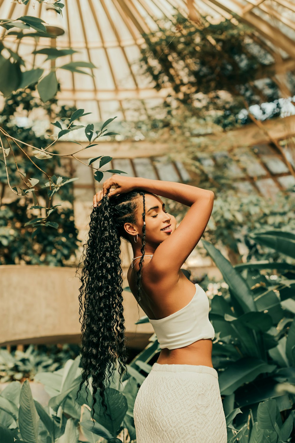 a woman with long hair standing in a greenhouse