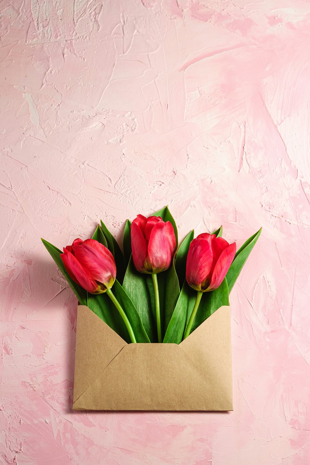 a bouquet of red tulips in a brown envelope