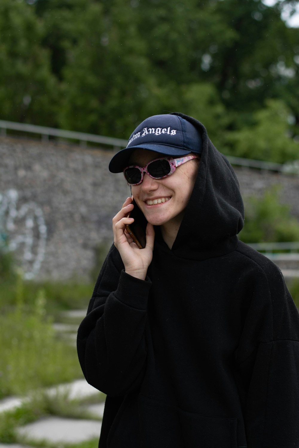 a woman in a black hoodie talking on a cell phone