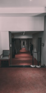 a hallway with a red carpet and two chairs