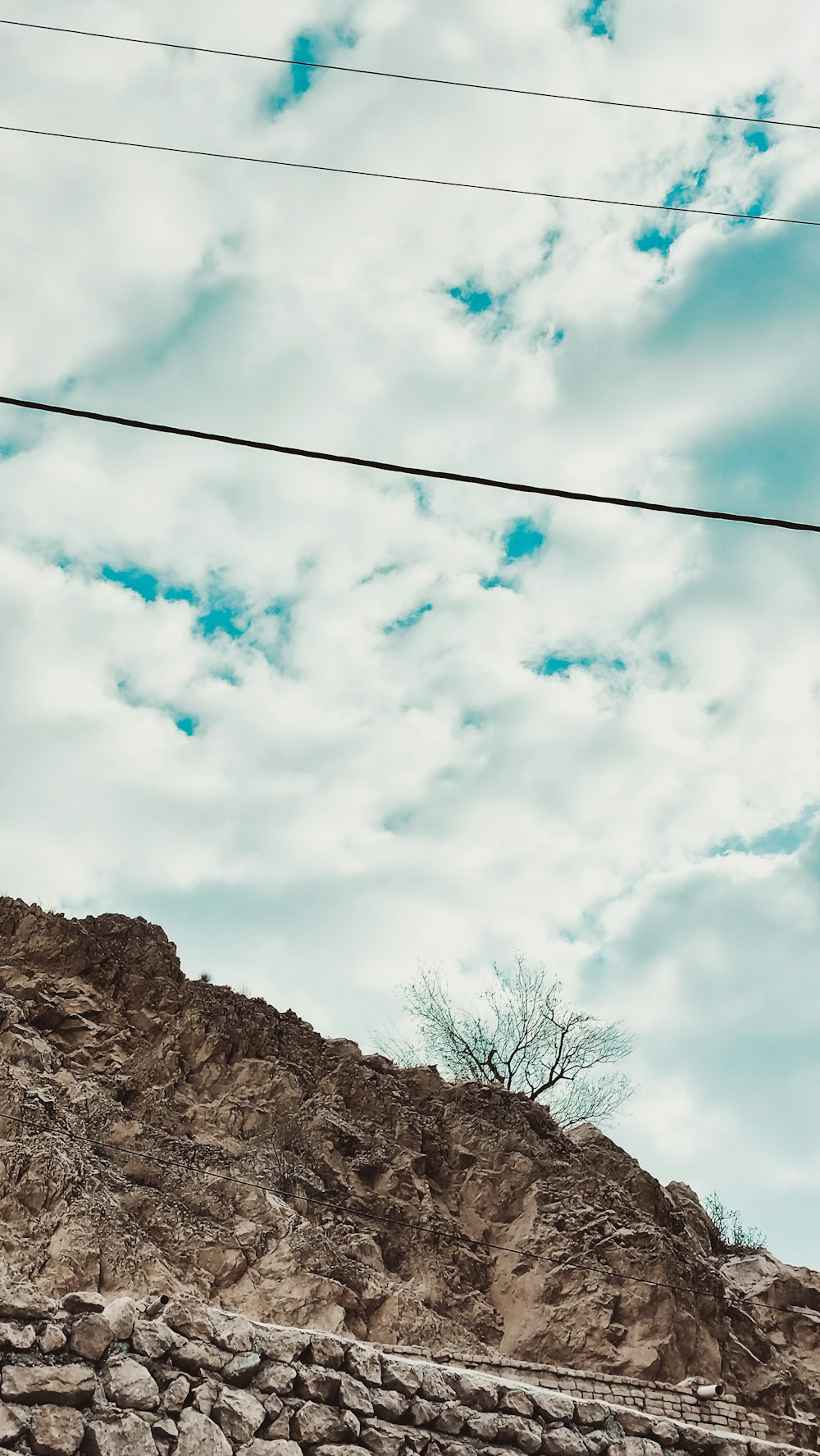 there is a rock wall and a telephone pole on the side of the hill