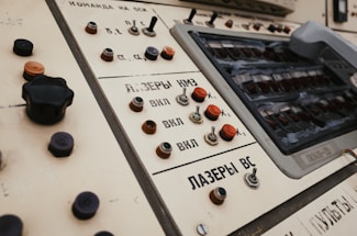 Control panel featuring various buttons, switches, and dials. The panel includes text in Cyrillic script and appears vintage, with wear visible on some components.