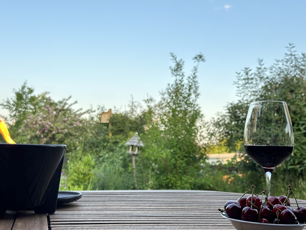 a bowl of fruit and a glass of wine on a table