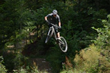 A mountain biker captured mid-air against a rugged forest backdrop.