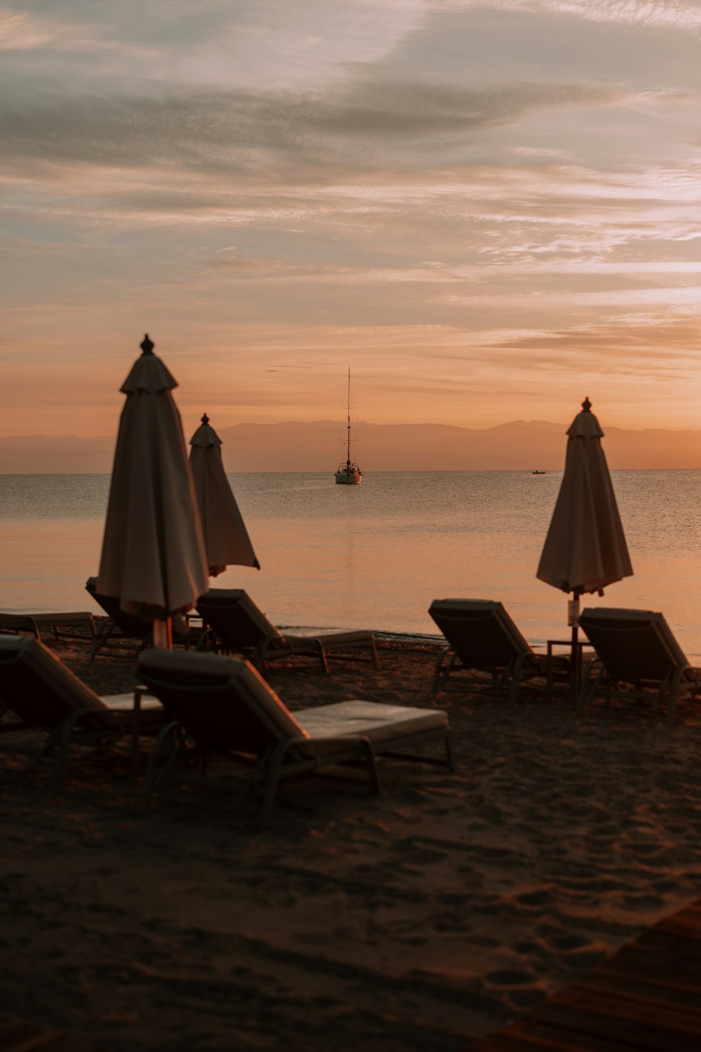 lounge chairs and umbrellas on a beach at sunset