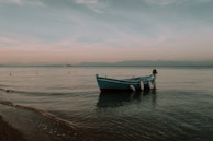A center console boat anchored peacefully with a backdrop of a pastel-colored sky at dusk.