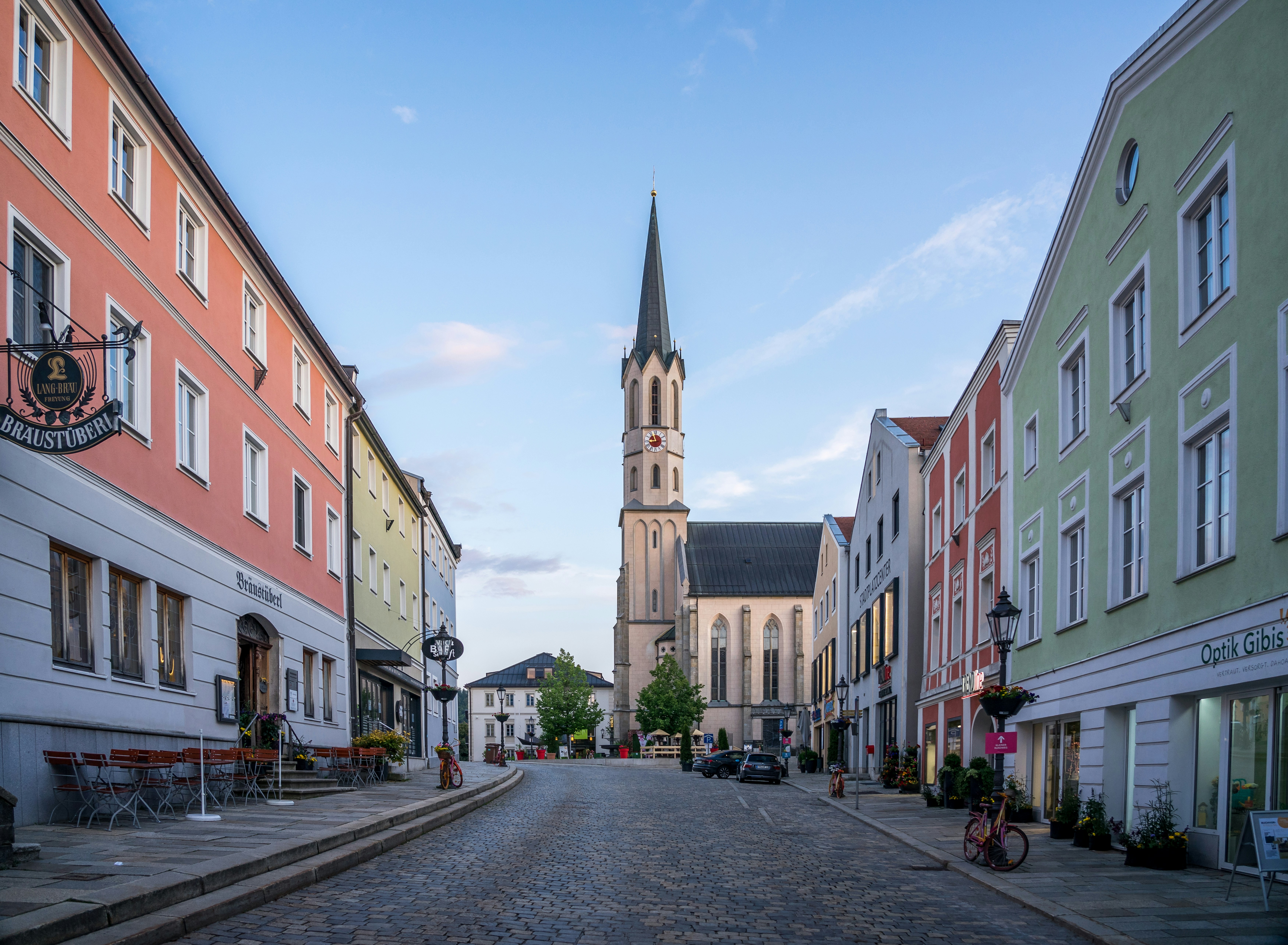 a cobblestone street with a church steeple in the background, 
