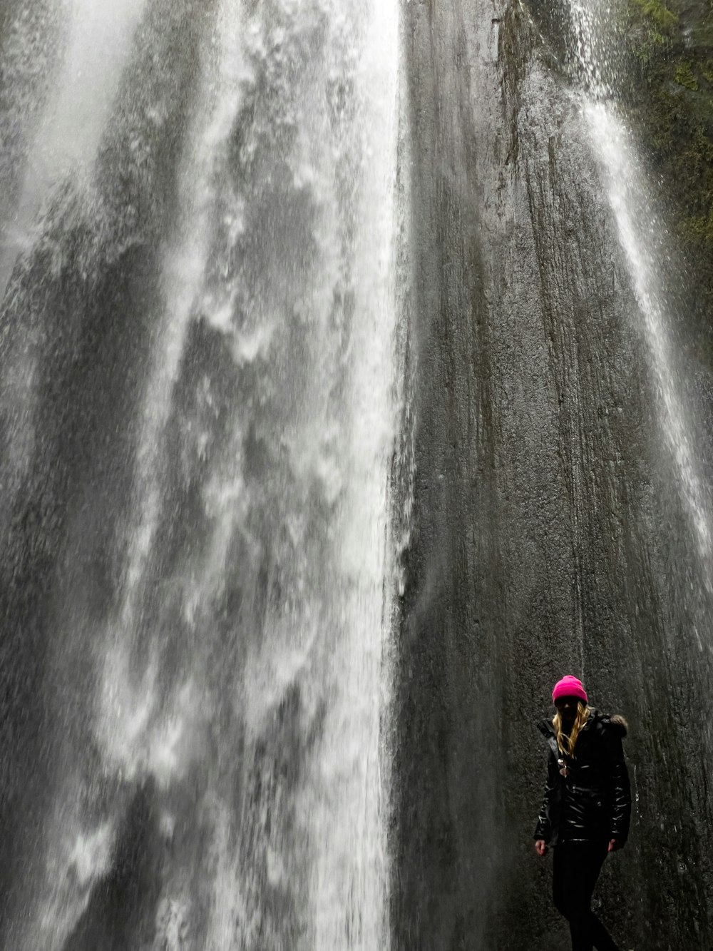 Una persona parada frente a una cascada