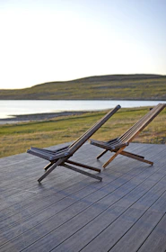 Relaxing deck chairs with wooden details overlooking the tranquil waters of Igaratá at golden hour.