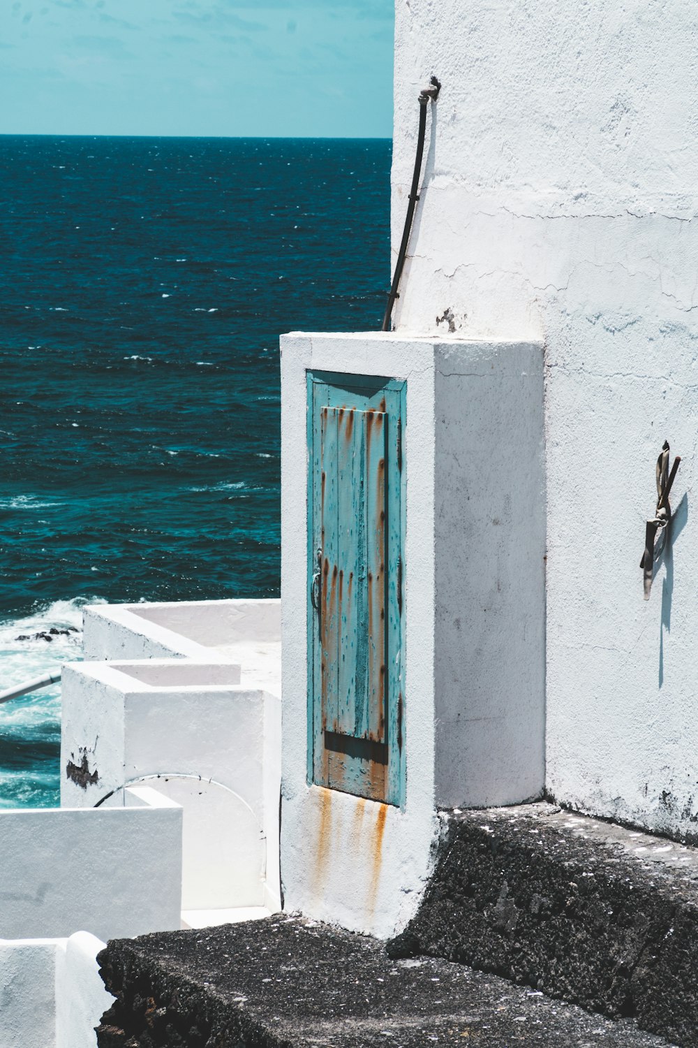 an open door on the side of a building next to the ocean