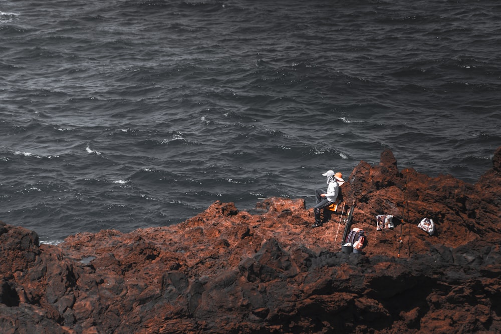 a group of people standing on top of a rocky cliff next to the ocean