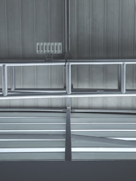 Metallic beams and supports form a structured pattern against a ribbed industrial ceiling. Several rectangular vents or panels are visible, adding to the utilitarian design.