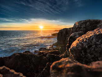 A breathtaking aerial shot of a turquoise ocean meeting rugged coastline at sunset.
