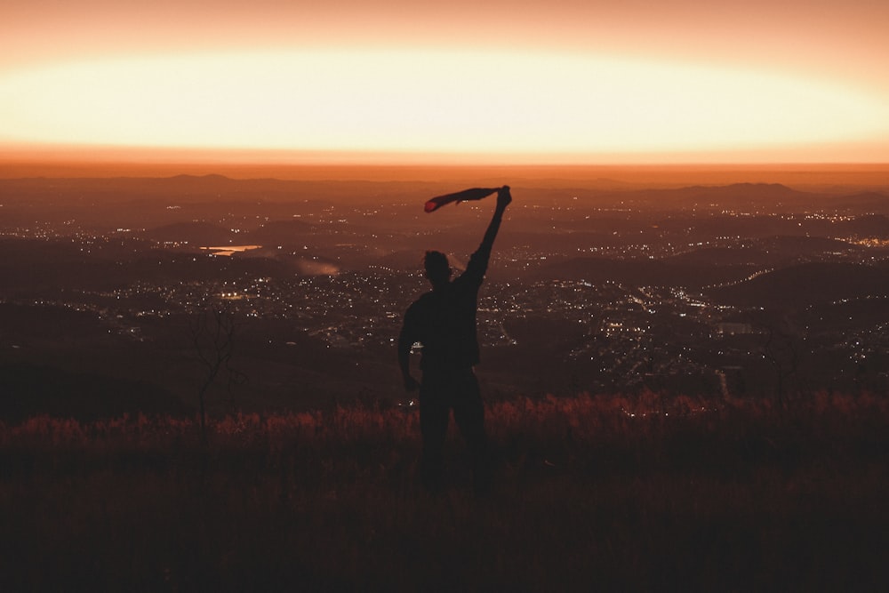 a man holding a flag on top of a hill