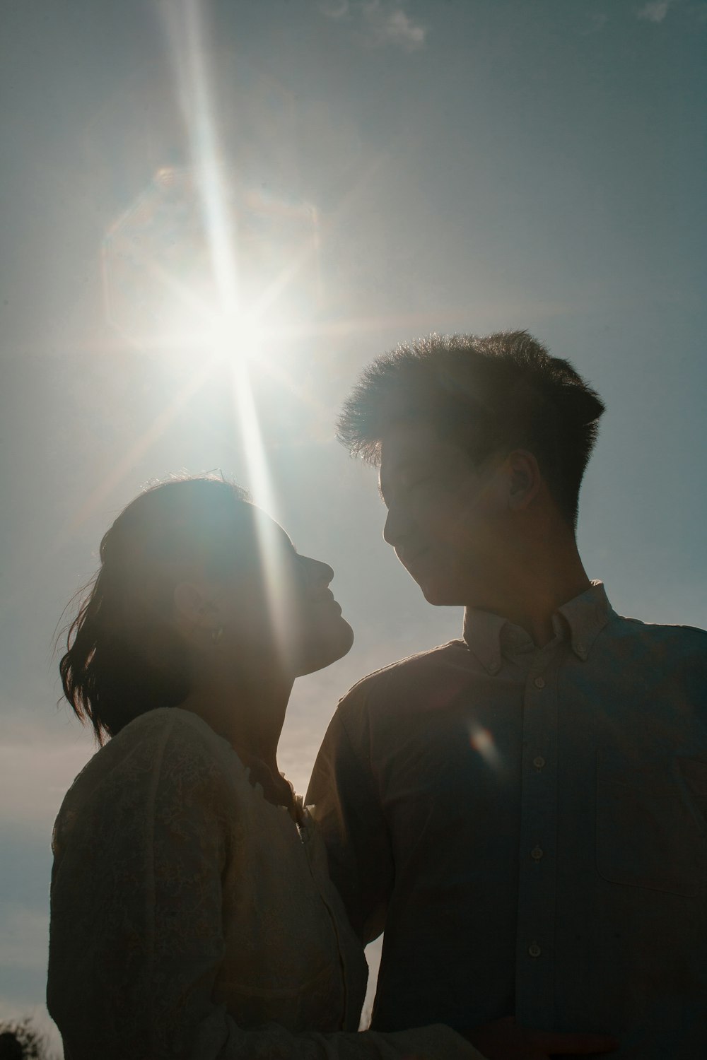 a man and a woman standing in front of the sun