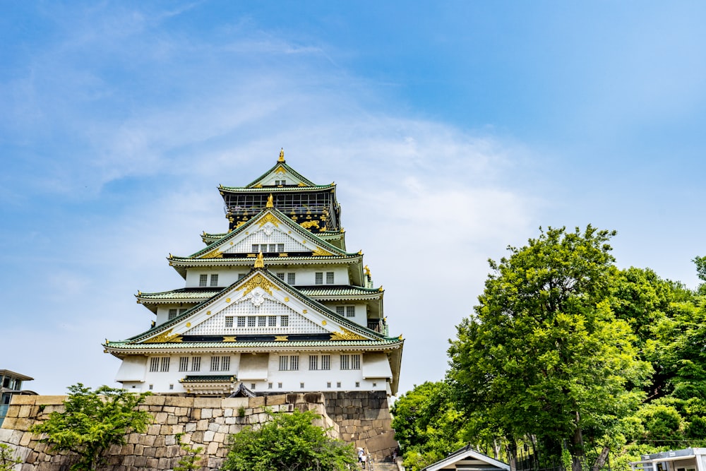 a tall white and gold building sitting next to a forest