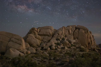 A futuristic space rover navigating rocky terrain under a starry sky.