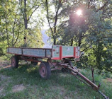 A cozy mobile home with wooden exterior surrounded by green trees on a sunny day.
