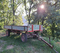 Sunlight filtering through the trees onto a Rumbolibre trailer with camping gear neatly arranged.
